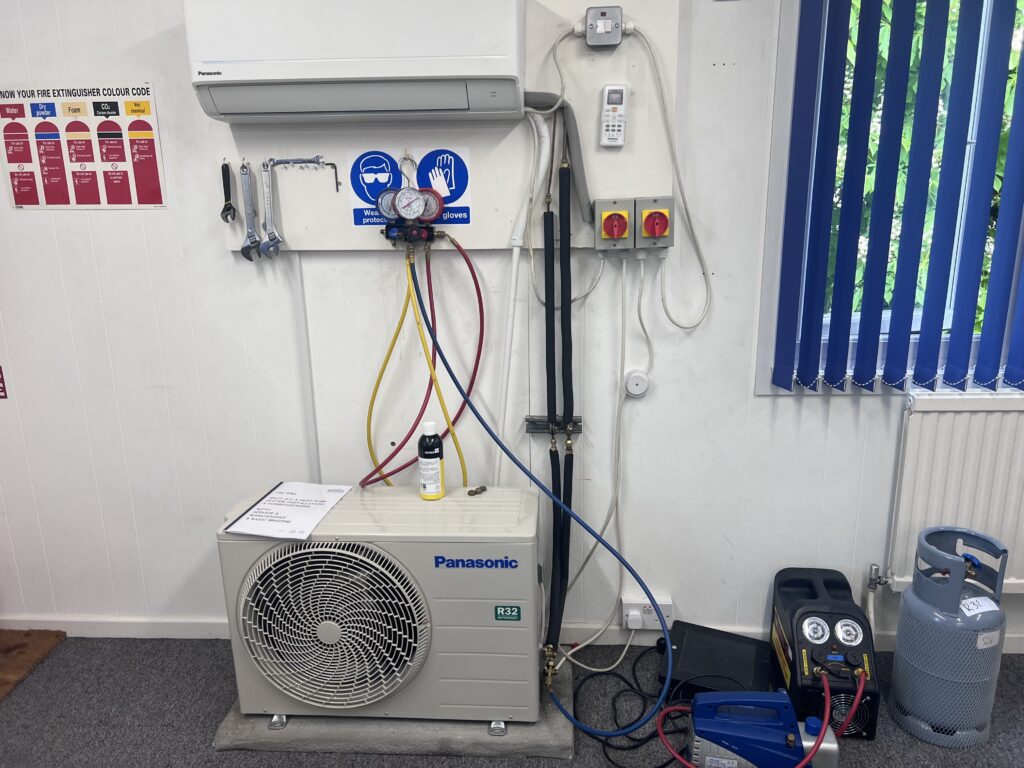 Air conditioning outdoor unit on wall brackets with gauges connected, as we test every Stow Longa system