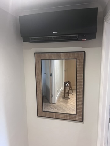Black Daikin air conditioning unit above a hallway mirror, the kind of system we fit in Ellington
