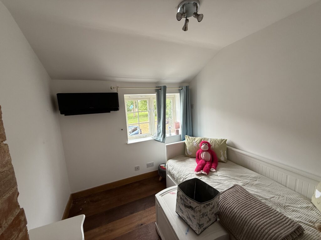 Black wall mounted air conditioning unit in a bedroom, the upstairs cooling St Neots homes ask for