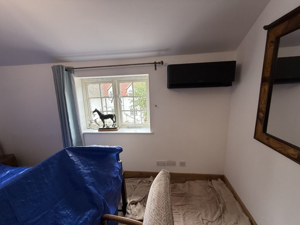 Black wall mounted air conditioning unit in a cottage bedroom, the bedroom systems we fit in Easton