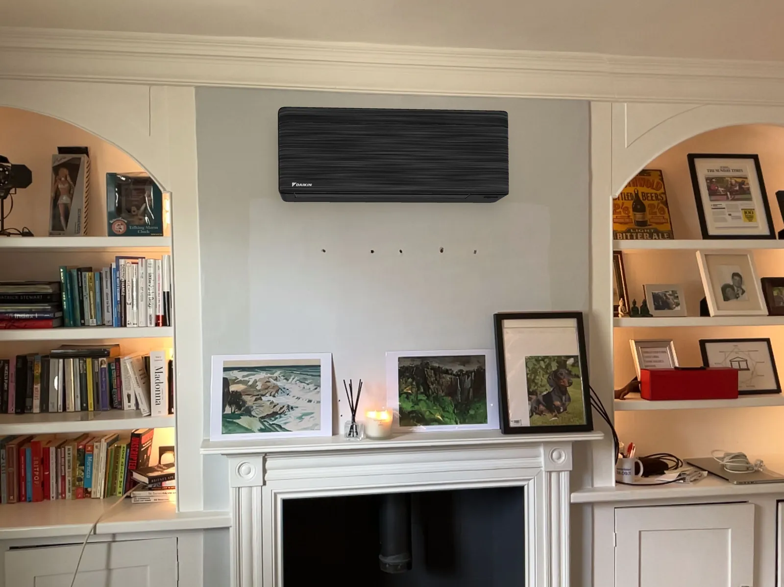 Black Daikin air conditioning unit above a fireplace and bookshelves, fitted by Selec Group