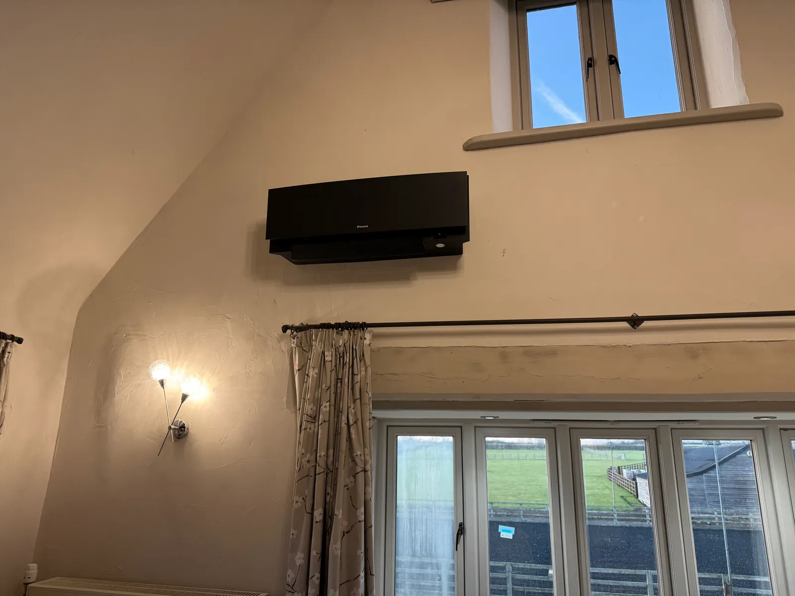 Black Daikin air conditioning unit high on a vaulted room wall in Raunds, installed by Selec Group
