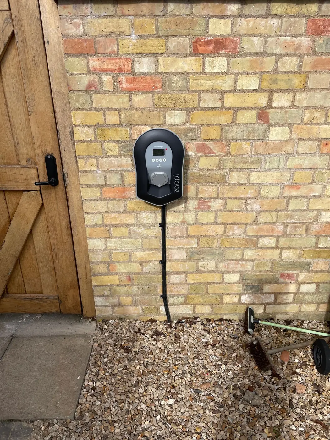 EV charger fitted on a brick wall beside a timber door, installed by Selec Group