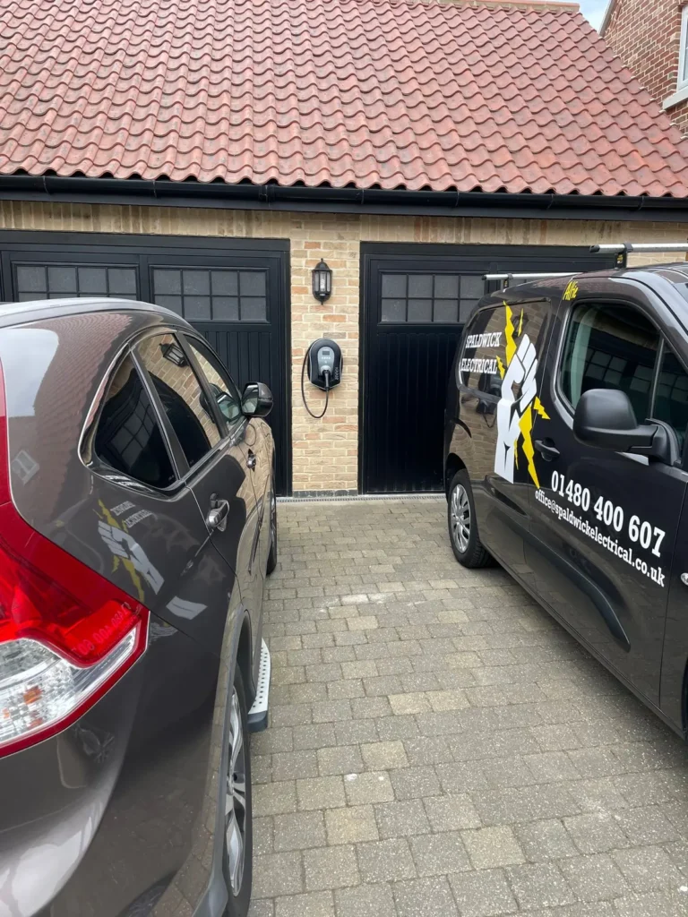 Our Spaldwick Electrical van beside a myenergi zappi EV charger we fitted on a garage wall