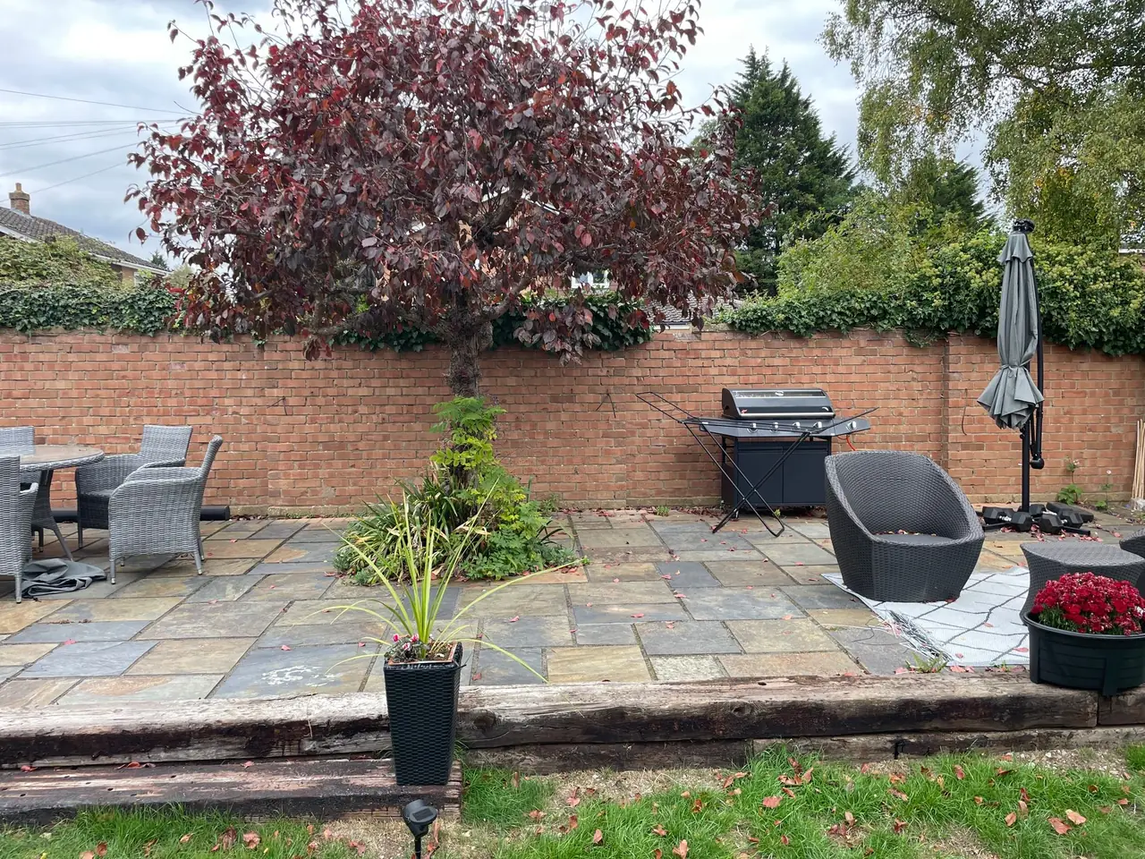 Garden lighting around a stone patio with a brick wall, installed by Selec Group