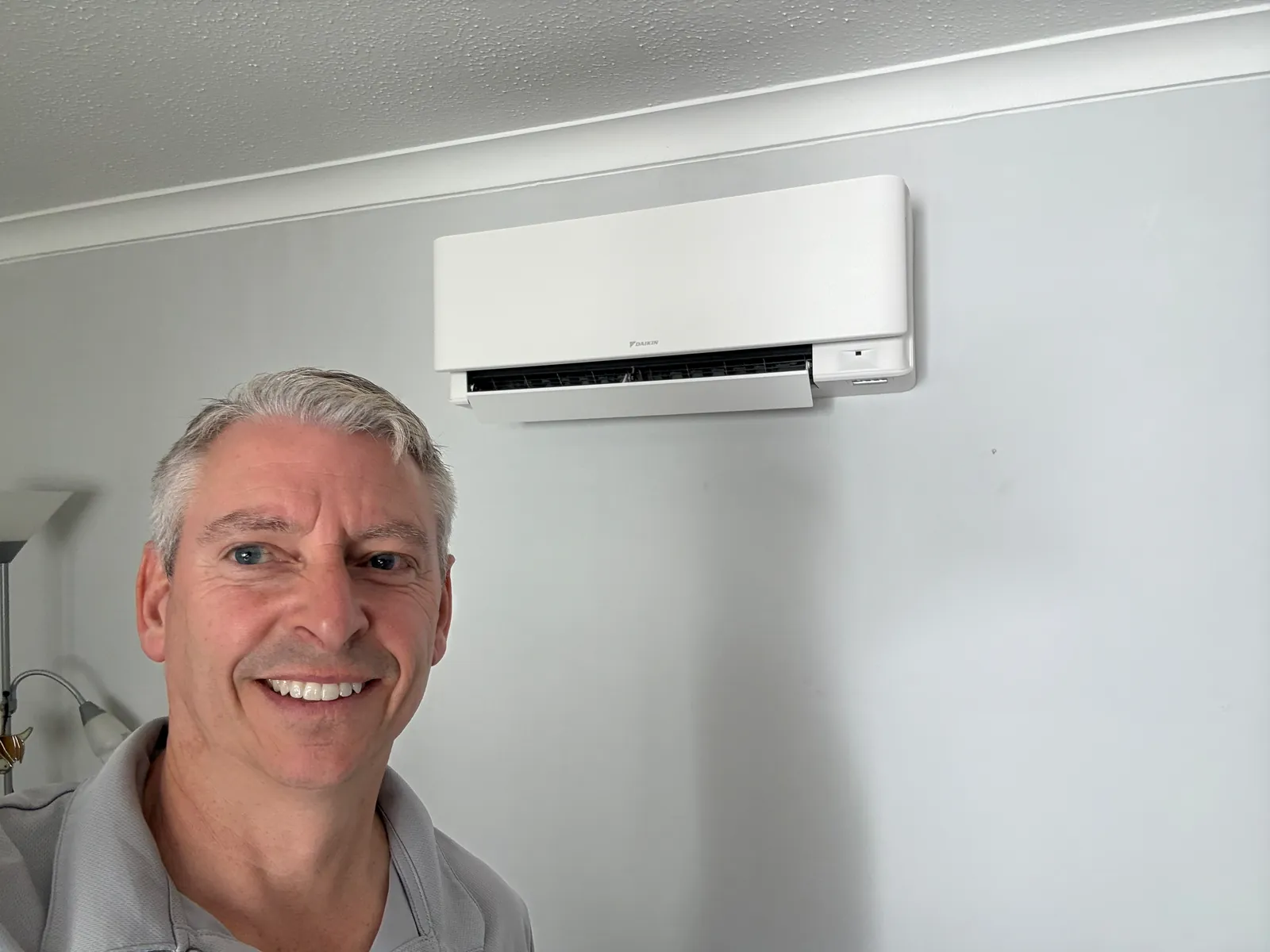 Jason Pope of Selec Group under a newly fitted white Daikin air conditioning unit in Perry