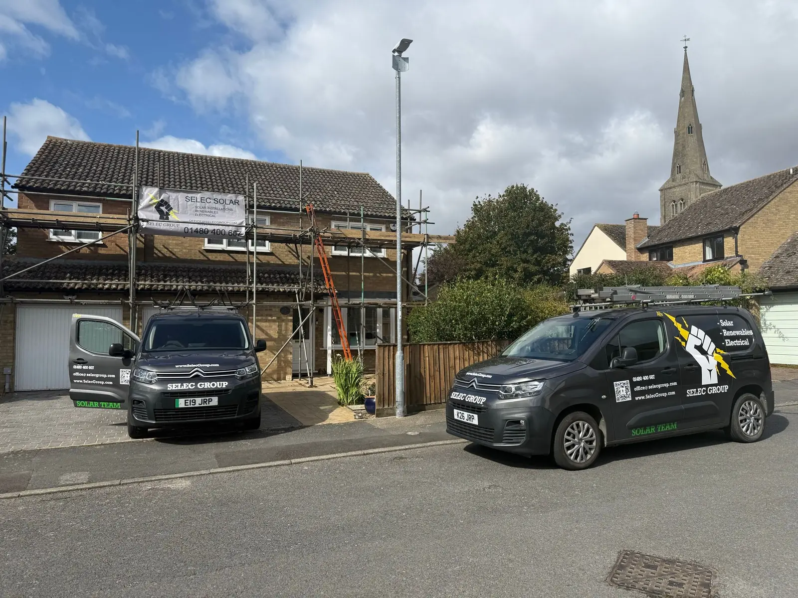 Selec Group vans and scaffold banner outside a solar install in progress