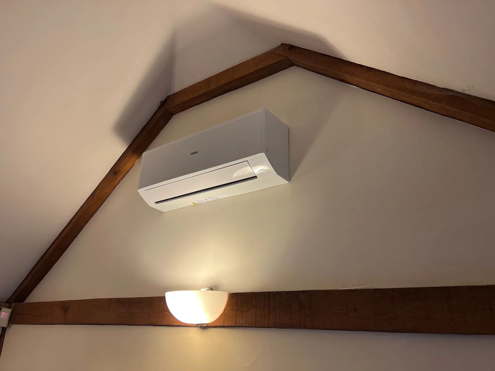 White air conditioning unit high on a vaulted ceiling wall in Stow Longa, fitted by Selec Group
